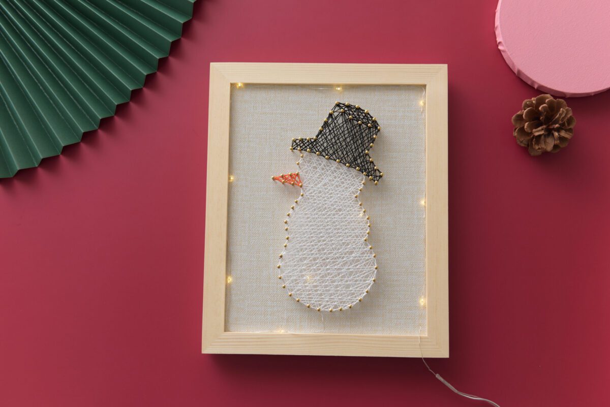 Snowman string art with black top hat and carrot nose
