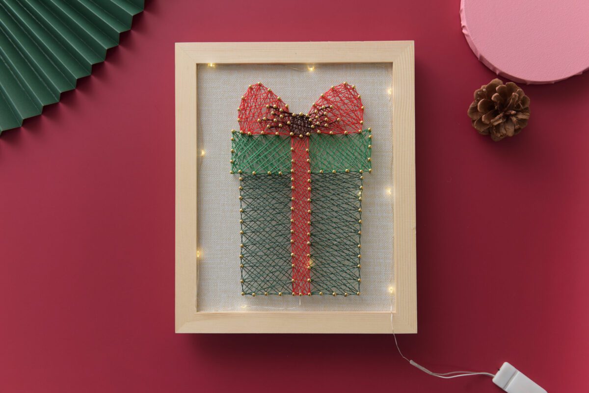 Gift box Christmas string art with red bow and green threads